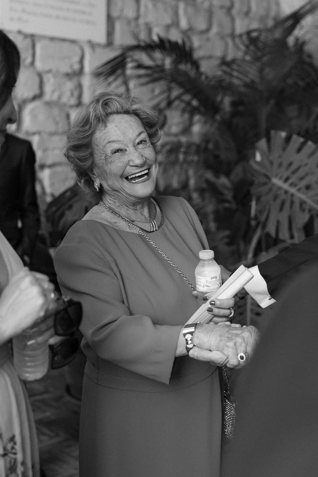 Retrato en blanco y negro de Marina riéndose al aire libre, delante de unas palmeras